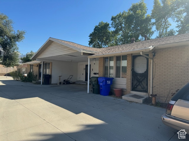 View of front facade with a carport, brick siding, and concrete driveway