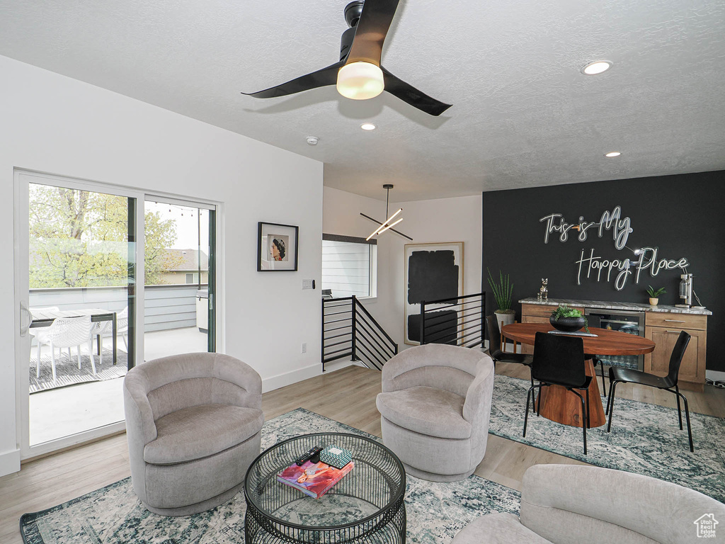 Living room featuring light wood-style floors, a chandelier, ceiling fan, recessed lighting, and wine cooler