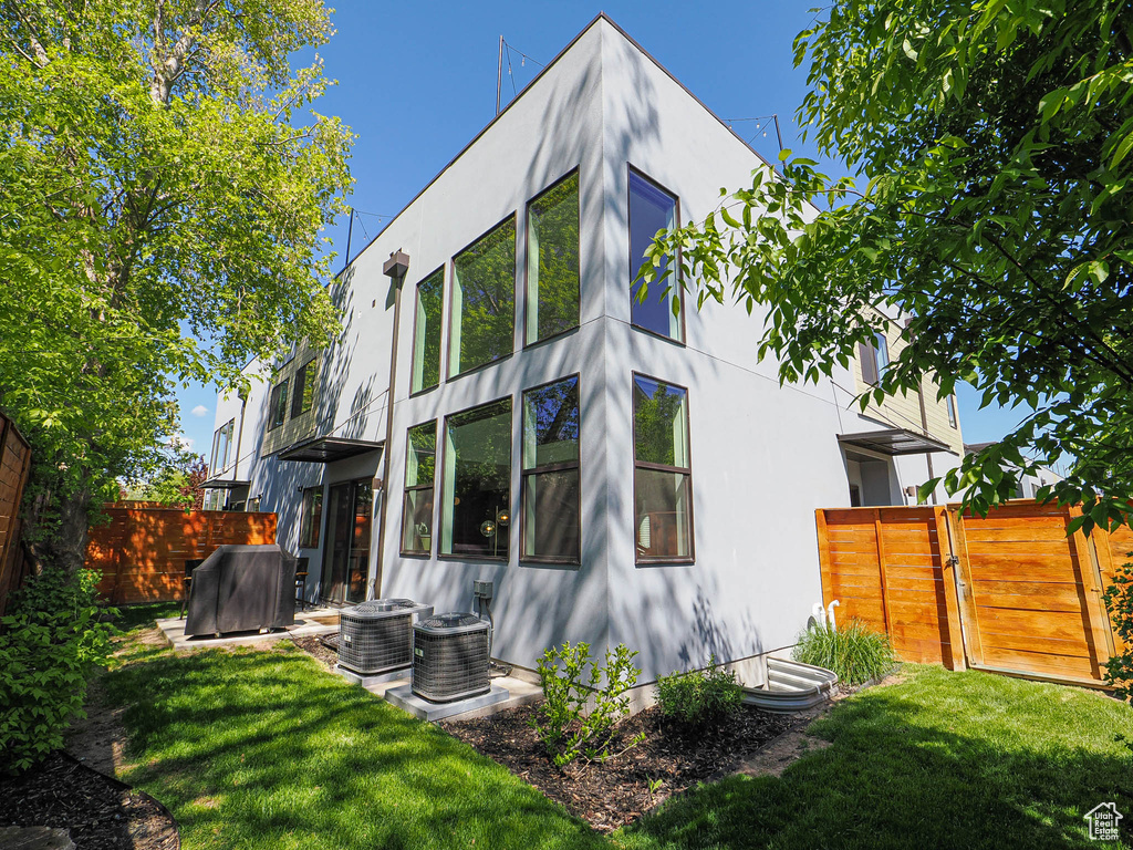 Back of house with stucco siding, cooling unit, and a gate