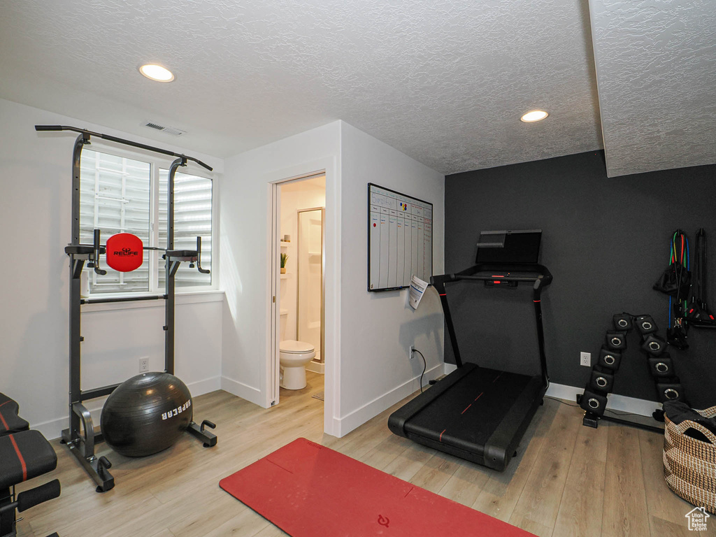 Exercise area with wood finished floors, a textured ceiling, baseboards, and recessed lighting