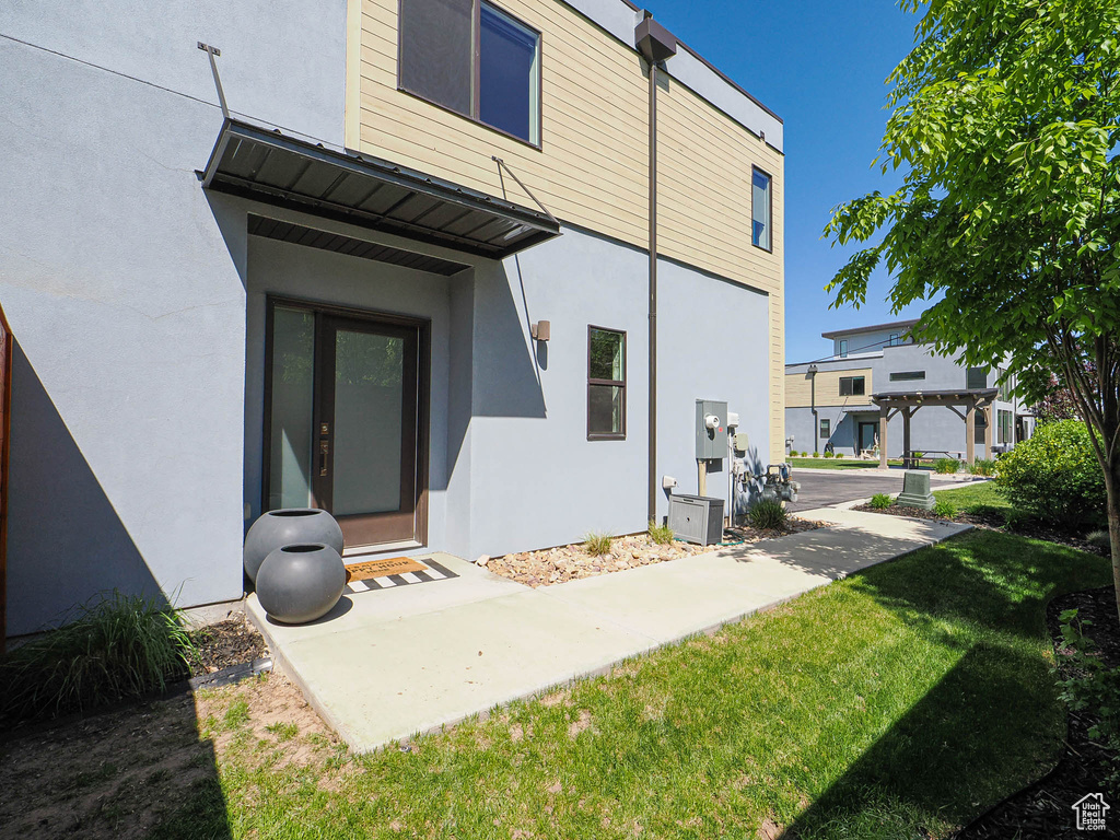 Back of house with stucco siding and a lawn