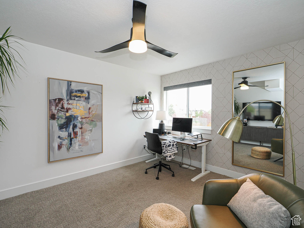 Carpeted office with a ceiling fan and baseboards