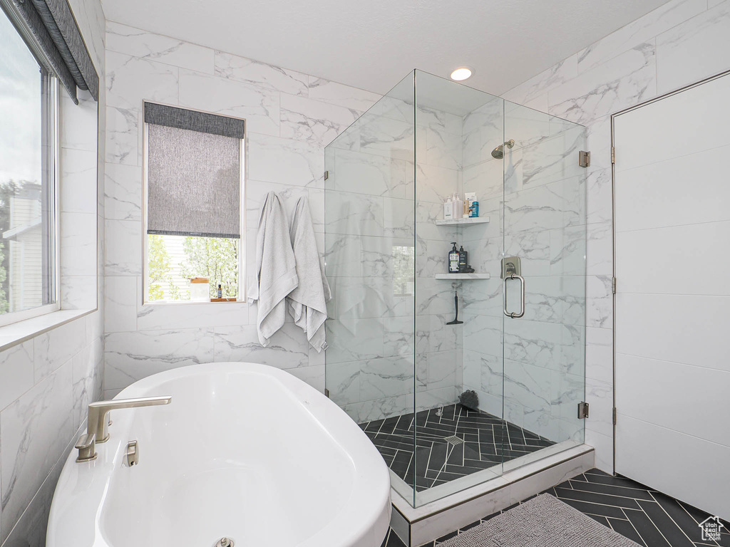 Full bath with a soaking tub, a marble finish shower, tile walls, and recessed lighting