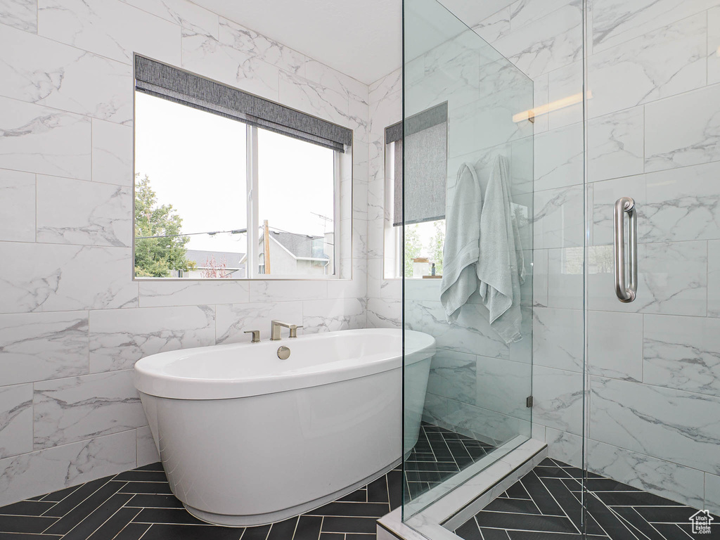 Bathroom featuring a freestanding tub, tile walls, and a shower stall