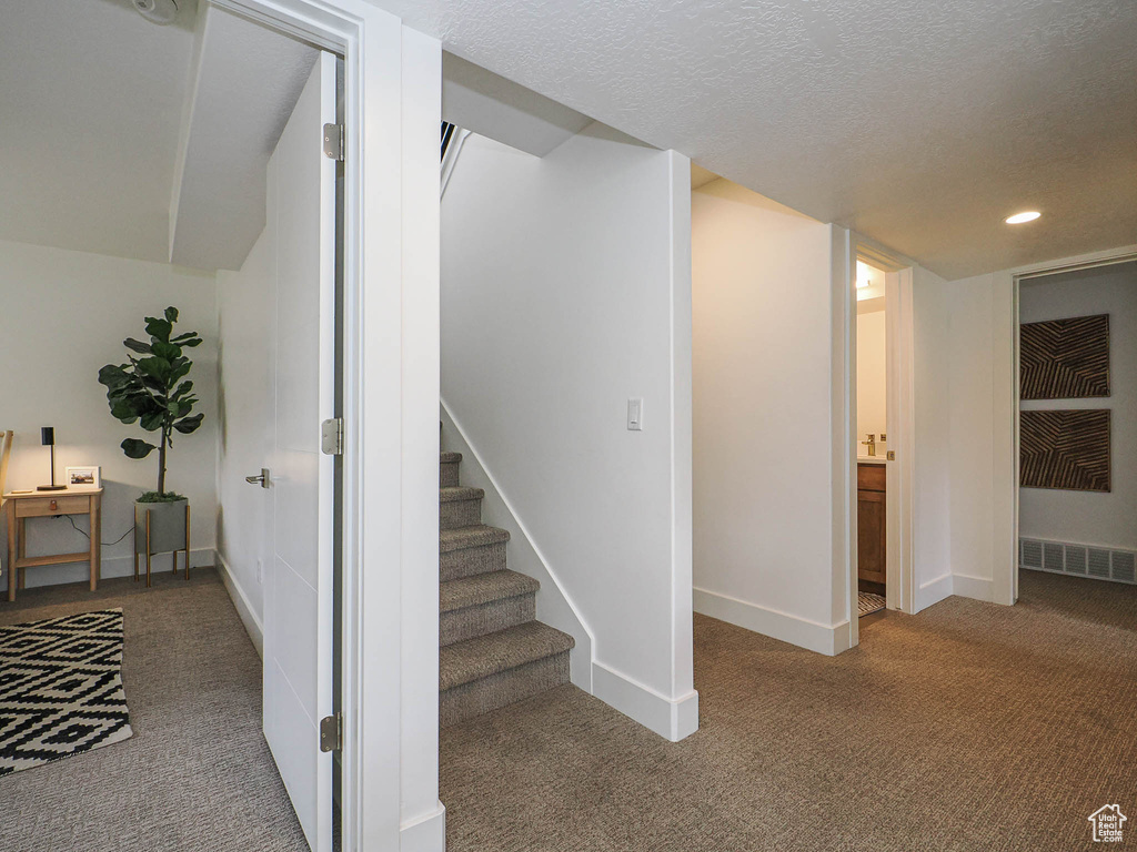 Stairway featuring carpet flooring, recessed lighting, baseboards, and a textured ceiling