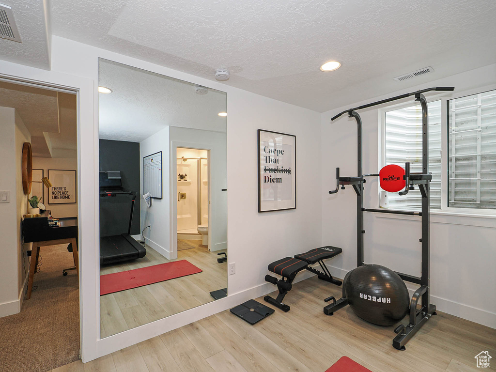 Exercise room with wood finished floors, baseboards, a textured ceiling, and recessed lighting