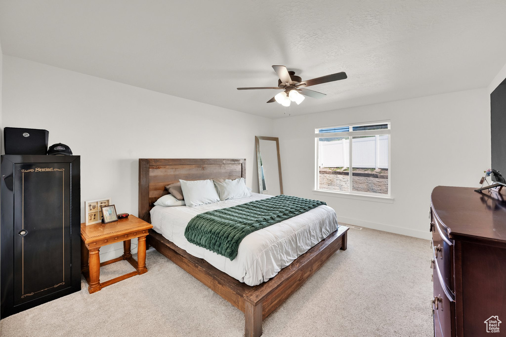 Bedroom featuring light colored carpet, baseboards, and a ceiling fan