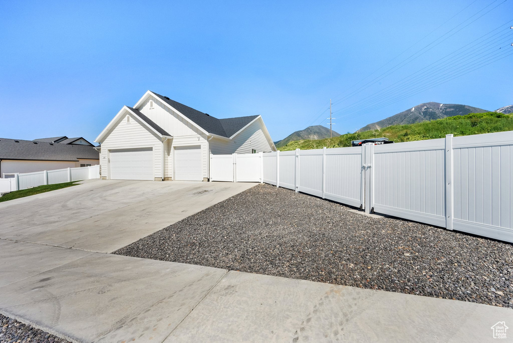 View of yard with a mountain view, a garage, driveway, and a gate