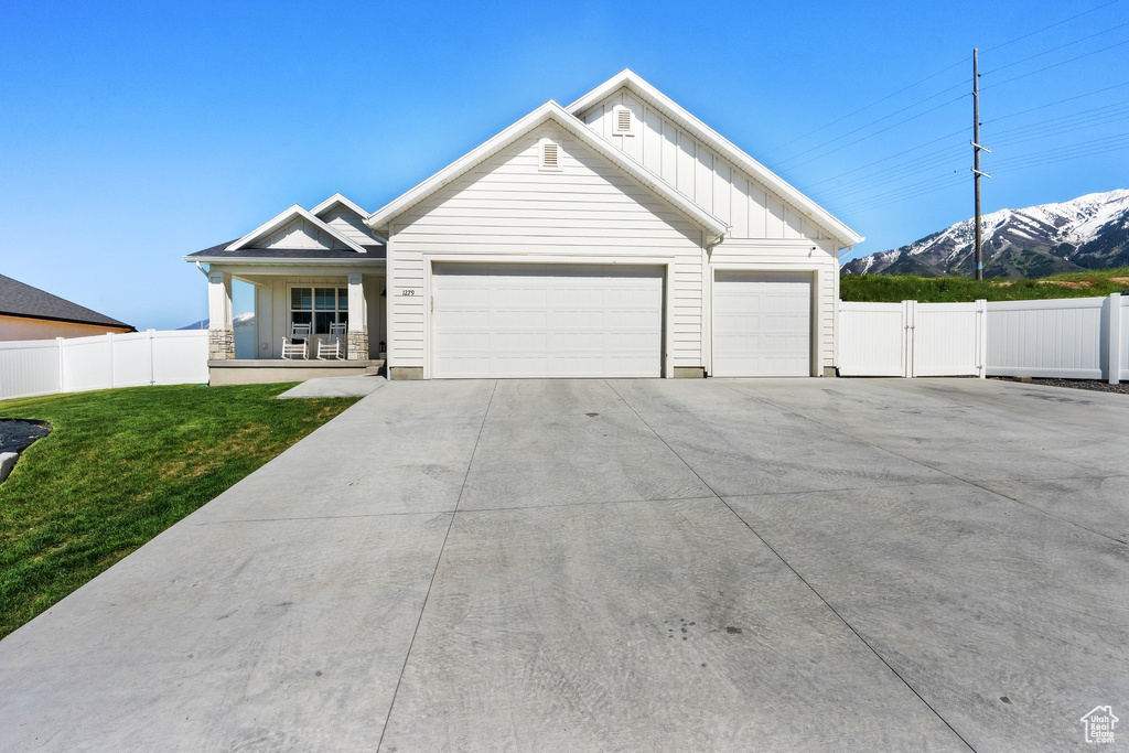 View of front of house featuring a mountain view, board and batten siding, driveway, a garage, and a porch