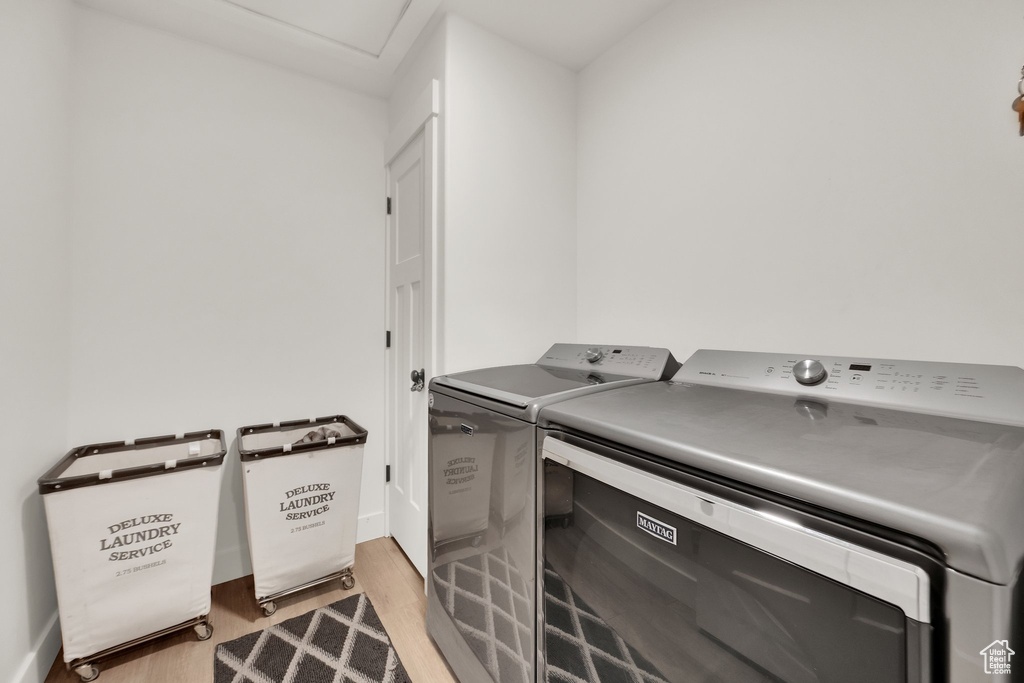 Laundry room featuring washer and dryer, light wood-type flooring, and baseboards