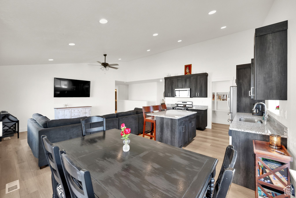 Dining space with a ceiling fan, light wood-type flooring, recessed lighting, and vaulted ceiling