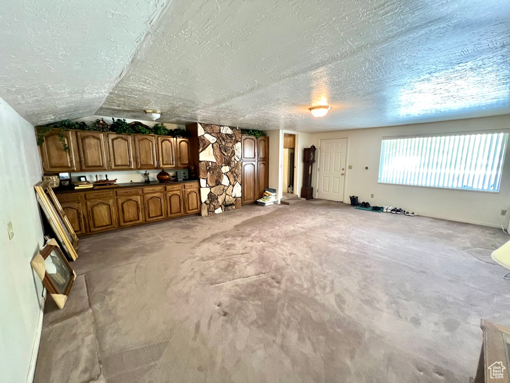 Unfurnished living room featuring a textured ceiling and light carpet