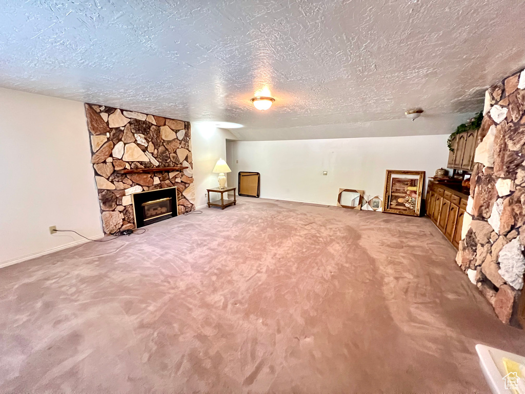 Unfurnished living room with a textured ceiling, a fireplace, and light colored carpet