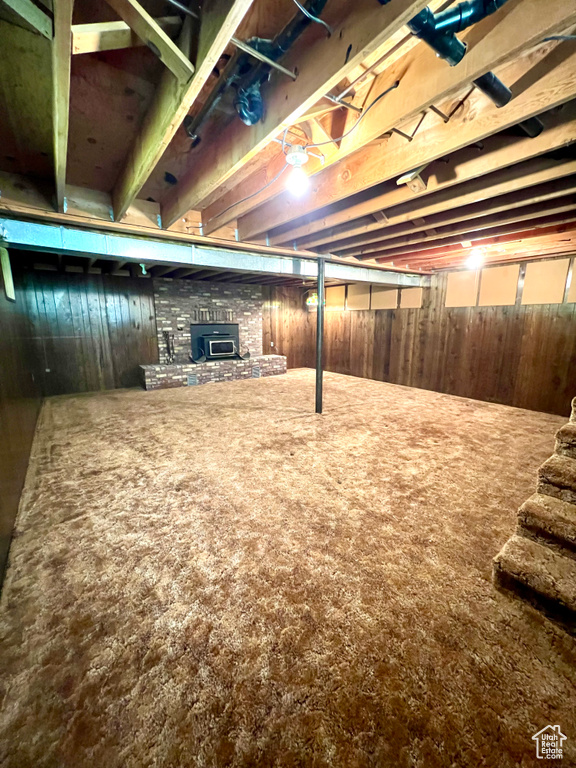 Basement with wooden walls, carpet floors, and a stone fireplace