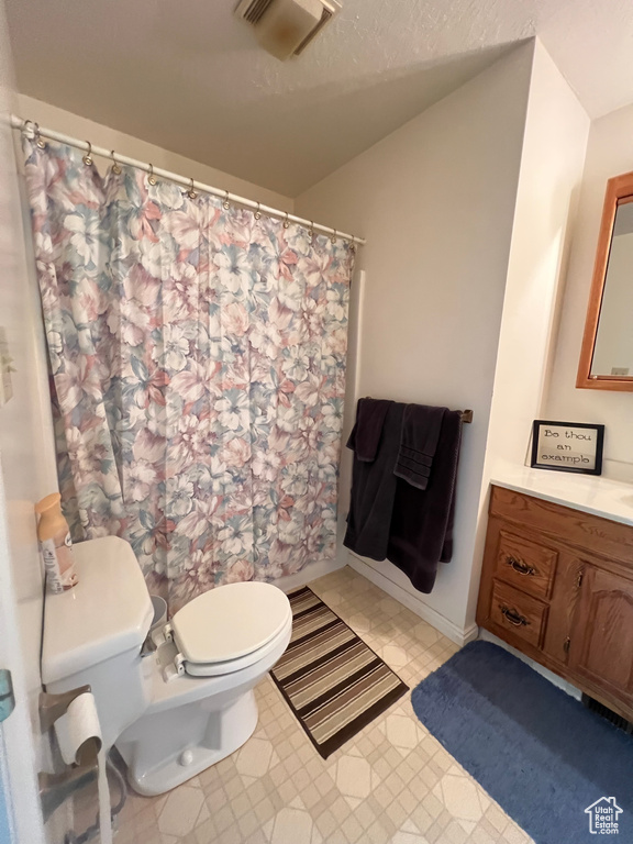 Bathroom featuring toilet, vanity, and a shower with shower curtain