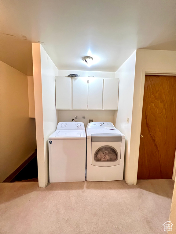 Washroom with cabinet space, independent washer and dryer, and light carpet