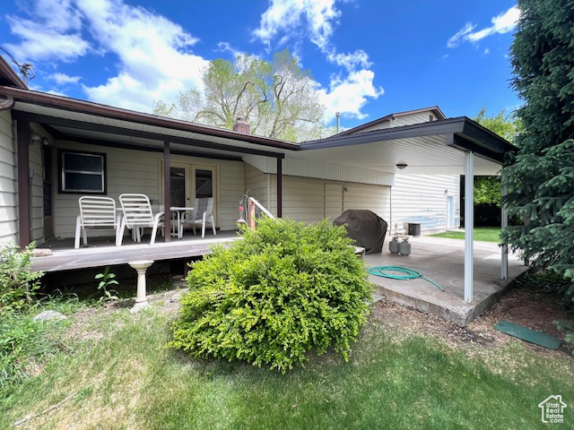Back of house with french doors, a patio area, a chimney, and a wooden deck