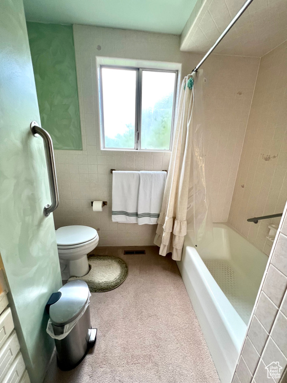 Bathroom with shower / bath combo, tile walls, and toilet