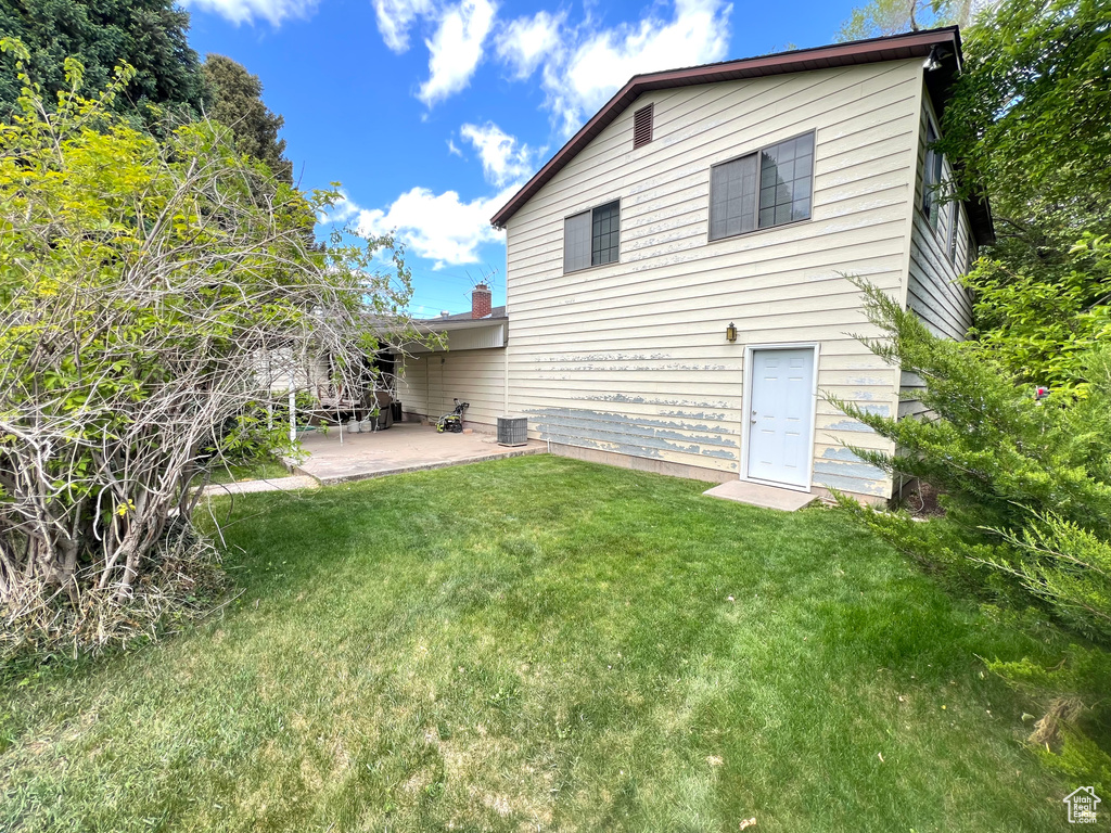 Back of house with a patio, a lawn, and cooling unit