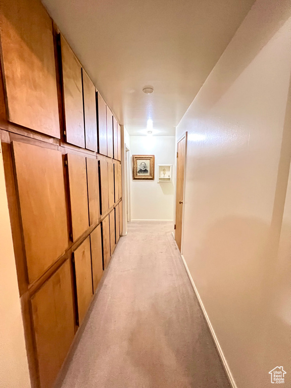 Hallway with light carpet and baseboards