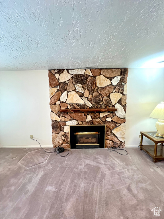 Detailed view of baseboards, a textured ceiling, a fireplace, and carpet