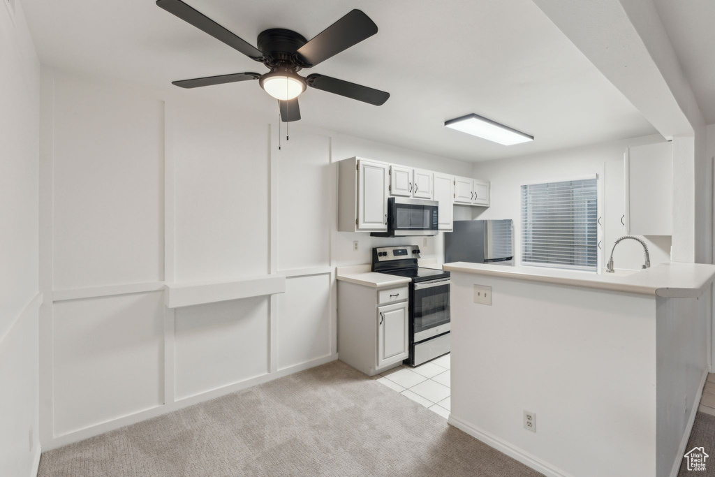 Kitchen with stainless steel appliances, light carpet, light countertops, a peninsula, and ceiling fan