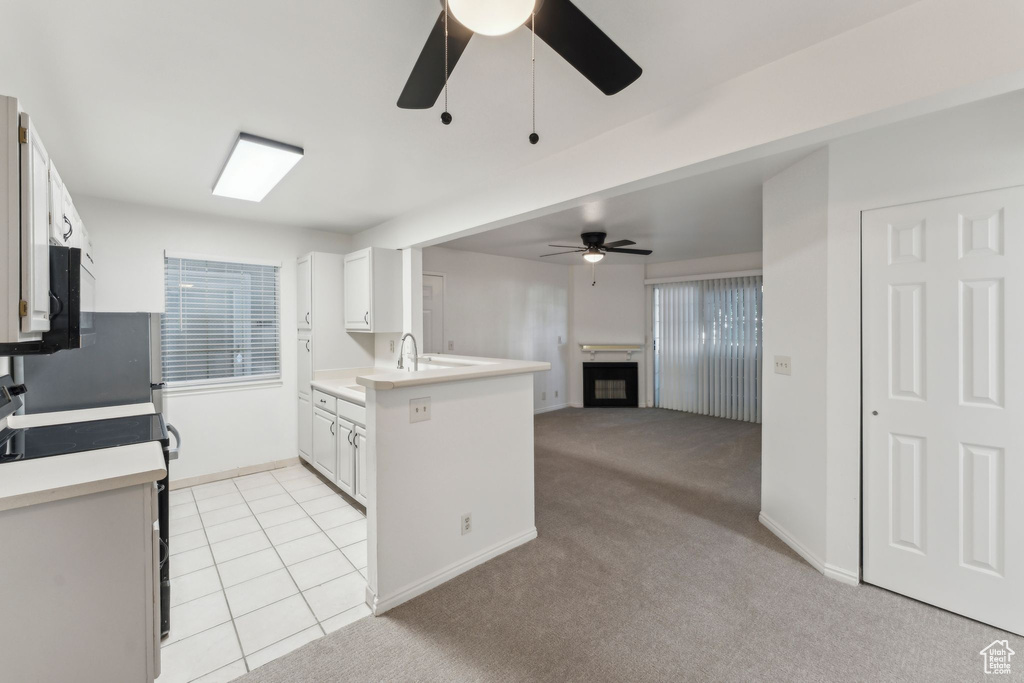 Kitchen featuring stove, ceiling fan, a peninsula, and light countertops