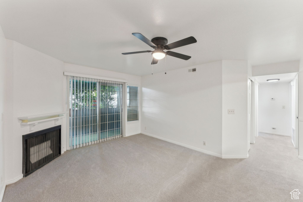 Unfurnished living room with carpet flooring, ceiling fan, a fireplace, and baseboards