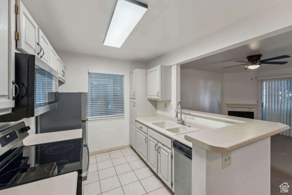 Kitchen featuring stainless steel appliances, a sink, a peninsula, ceiling fan, and light countertops