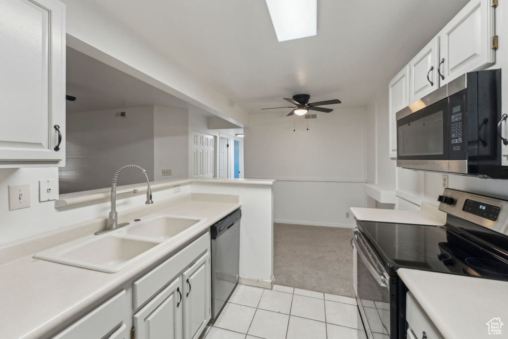 Kitchen featuring appliances with stainless steel finishes, a sink, light carpet, a ceiling fan, and white cabinets