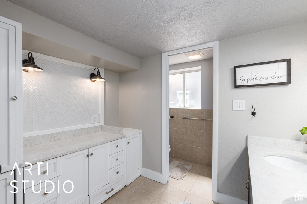 Full bathroom with vanity, tile patterned floors, a textured ceiling, and toilet