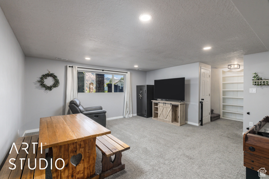 Carpeted living room with a textured ceiling, baseboards, and recessed lighting