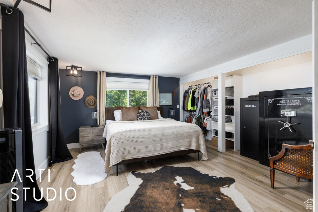 Bedroom with a textured ceiling and light wood finished floors