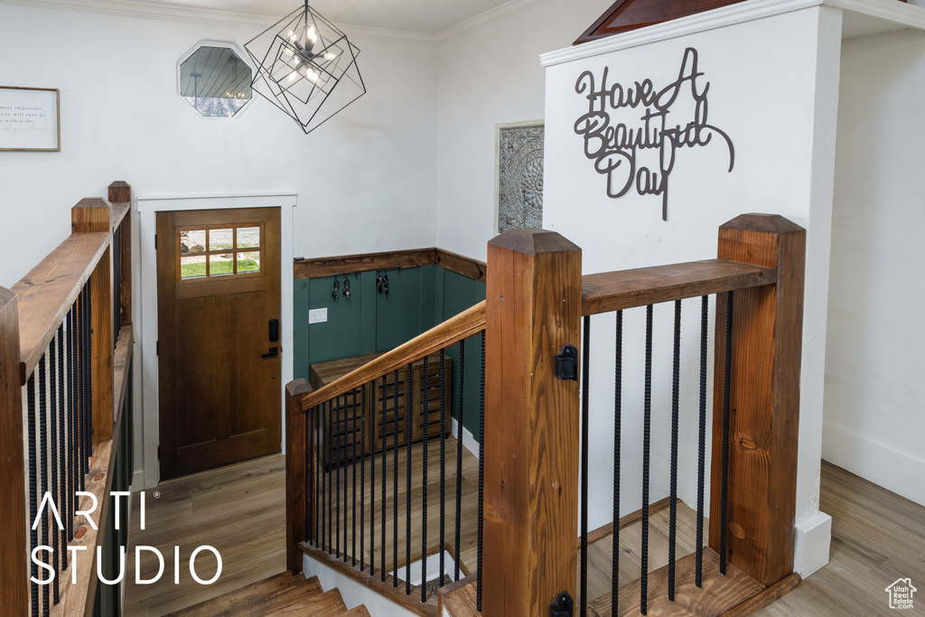 Foyer with wood finished floors, a chandelier, and ornamental molding
