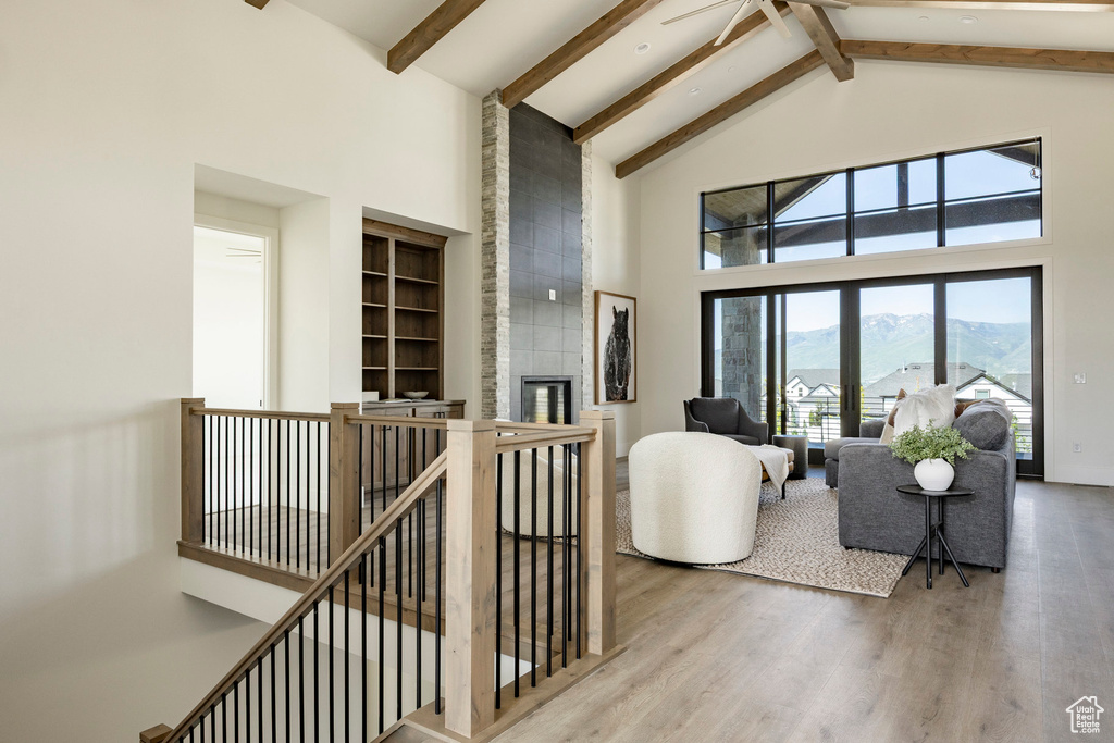 Living room with high vaulted ceiling, wood finished floors, beamed ceiling, a mountain view, and a fireplace