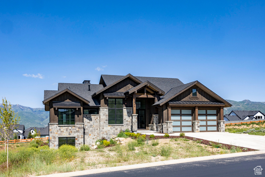 View of front of house featuring stone siding, a standing seam roof, board and batten siding, driveway, and a mountain view