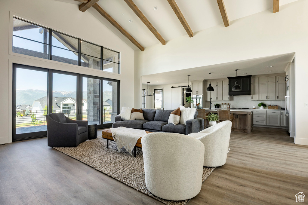 Living room with high vaulted ceiling, beam ceiling, and light wood-style floors
