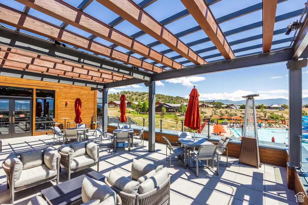 View of patio with outdoor dining space, a pergola, a mountain view, and french doors