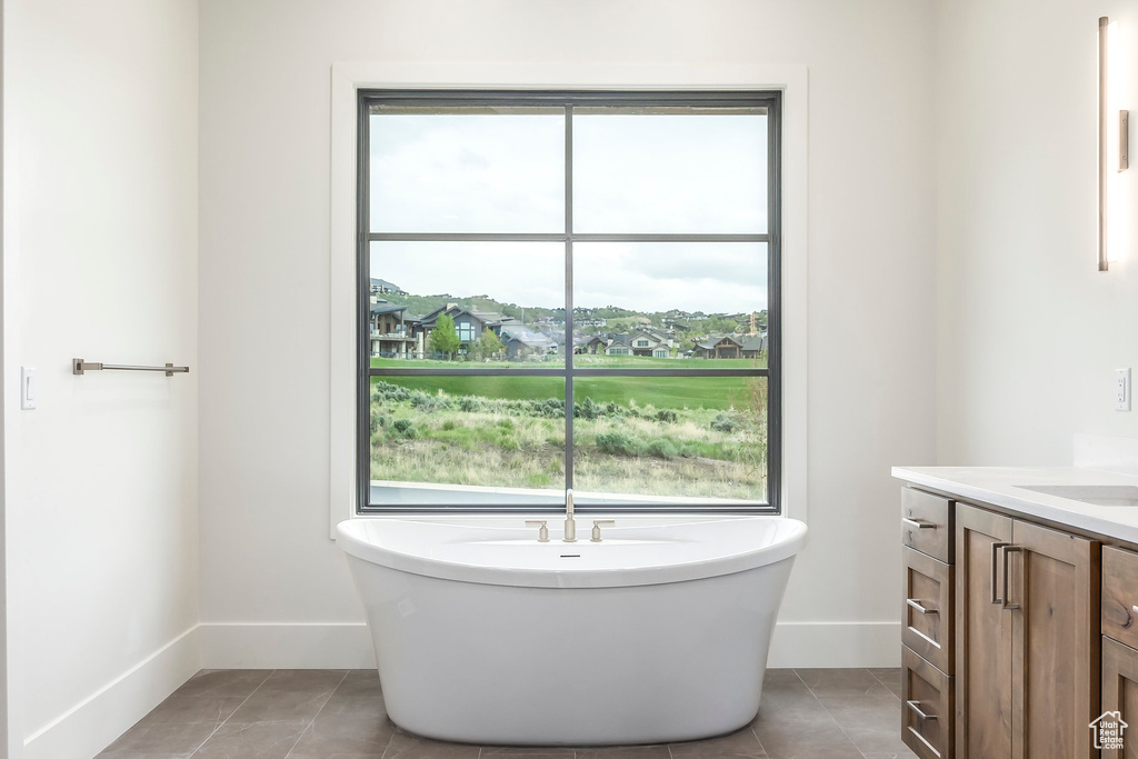 Bathroom featuring a freestanding bath, tile patterned floors, vanity, and baseboards