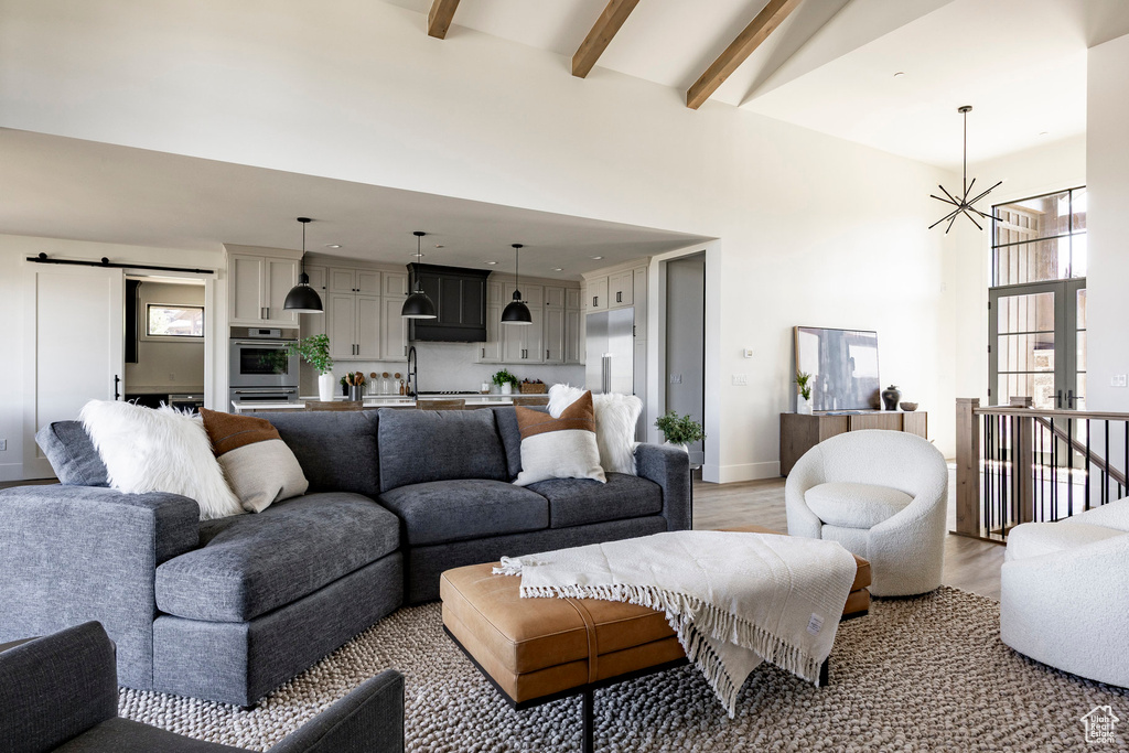 Living area with high vaulted ceiling, beamed ceiling, a chandelier, light wood-type flooring, and baseboards