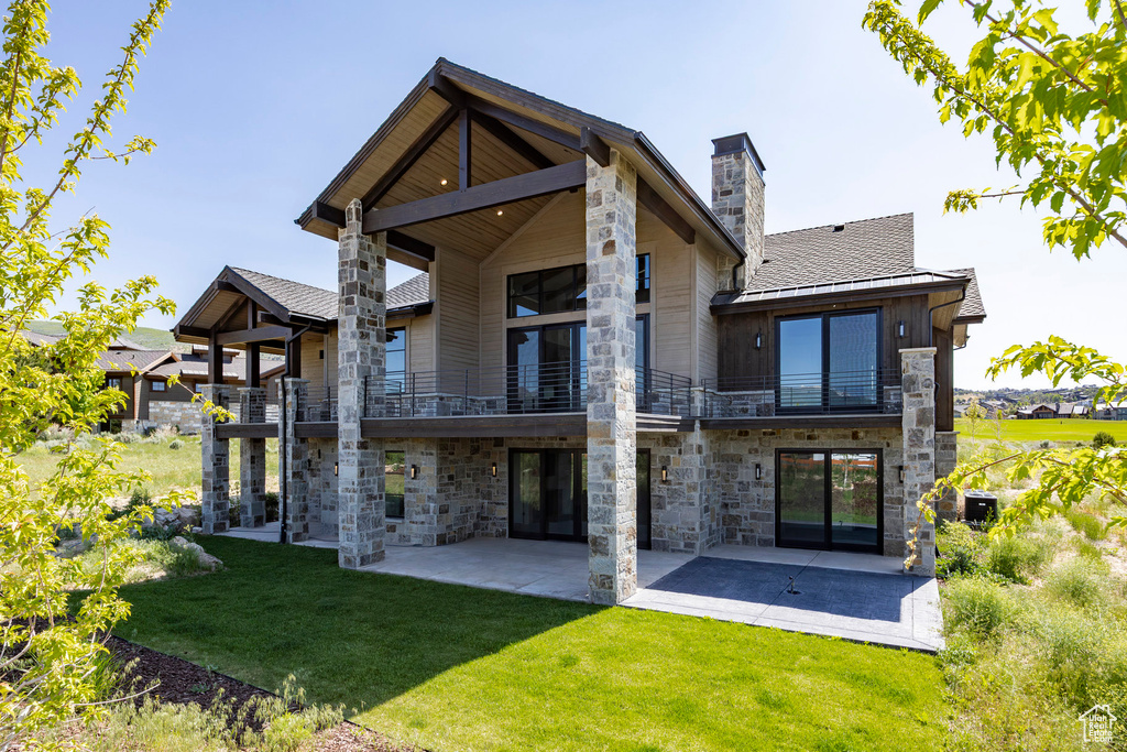 Back of house with a balcony and stone siding