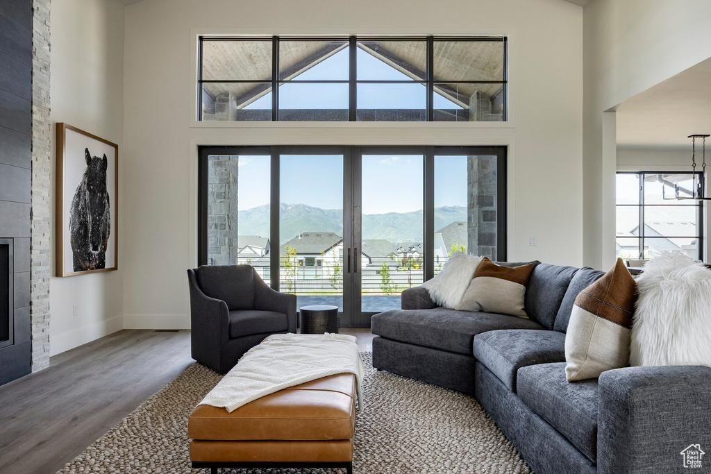 Living area with plenty of natural light, wood finished floors, a towering ceiling, baseboards, and a mountain view