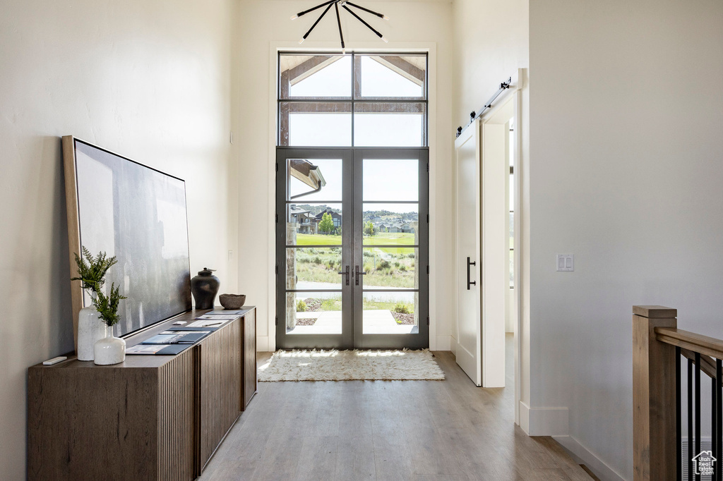 Entrance foyer featuring light wood finished floors, french doors, healthy amount of natural light, baseboards, and a towering ceiling