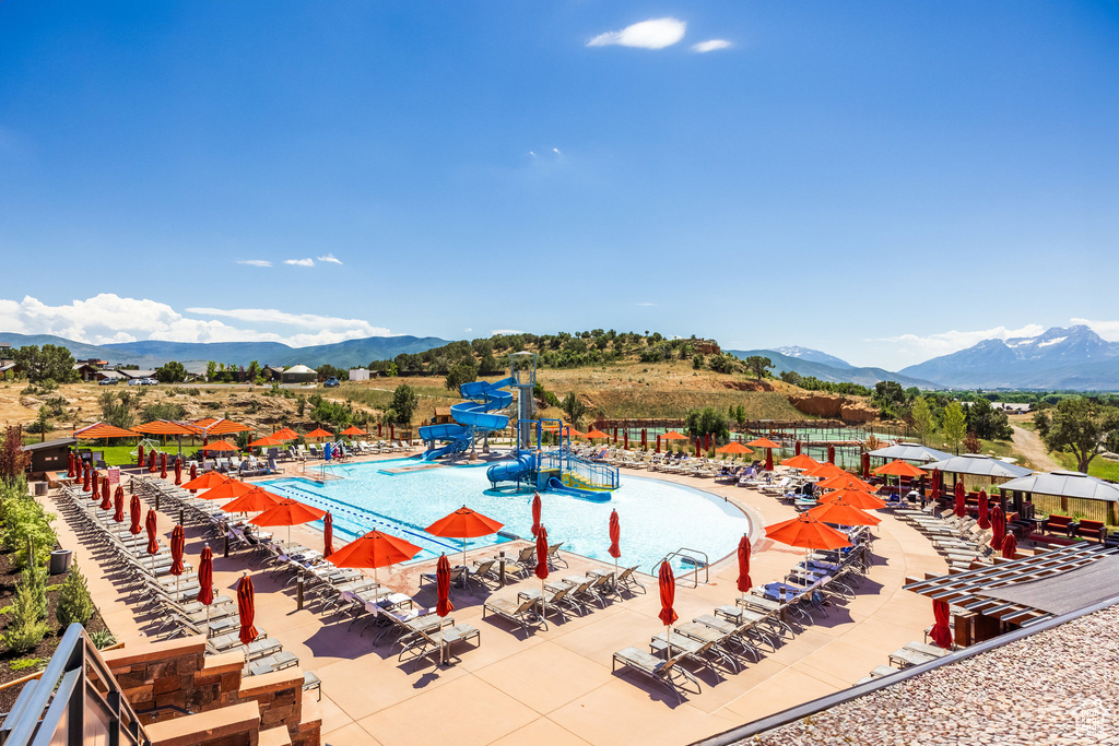 Community pool featuring a water slide, a mountain view, a water play area, and a patio
