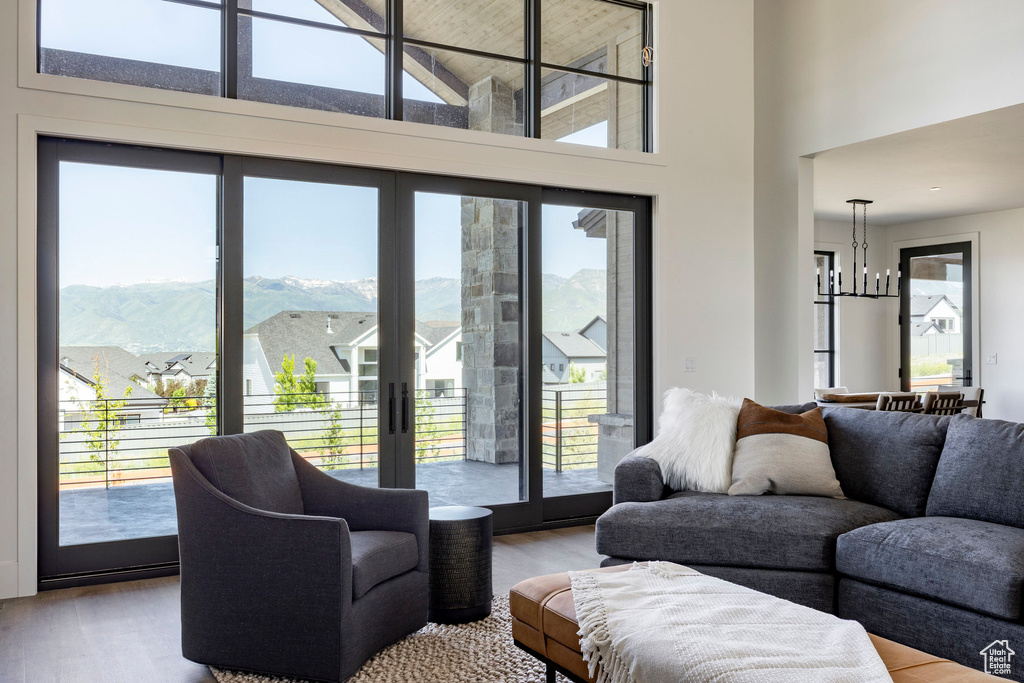 Living area with wood finished floors, healthy amount of natural light, a high ceiling, and a chandelier
