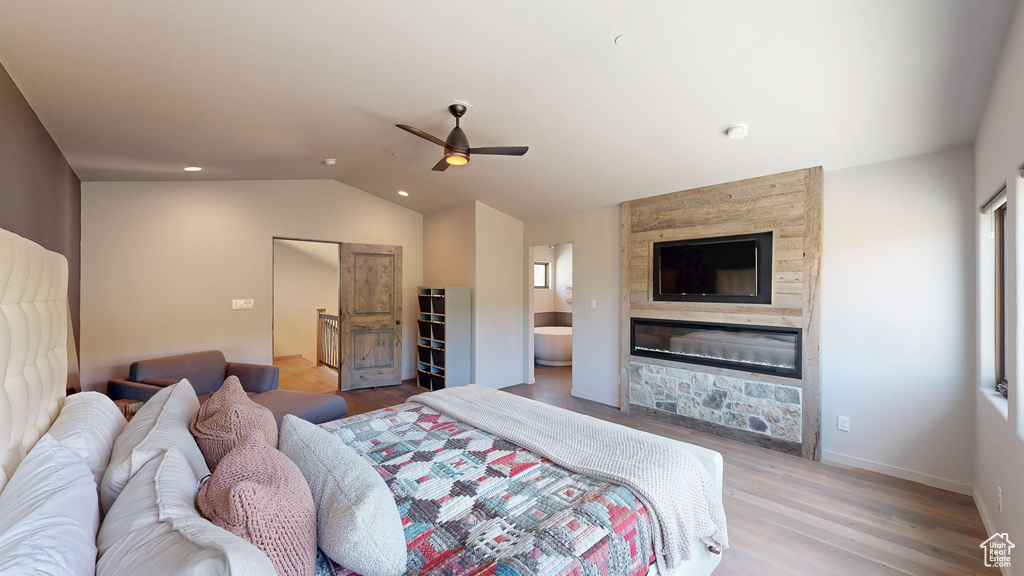 Bedroom with vaulted ceiling, a fireplace, wood finished floors, a ceiling fan, and baseboards
