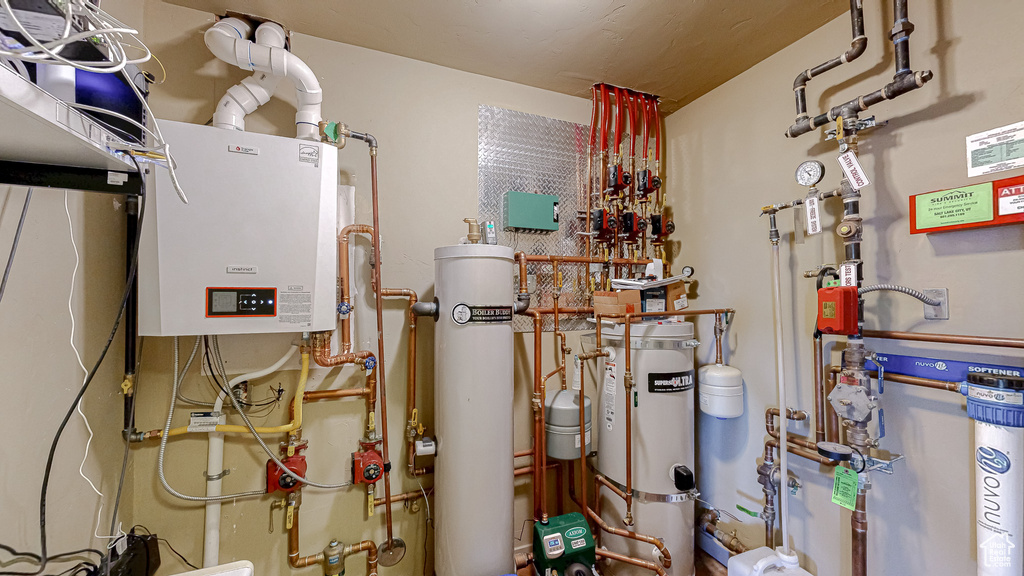 Utility room featuring secured water heater, tankless water heater, and water heater