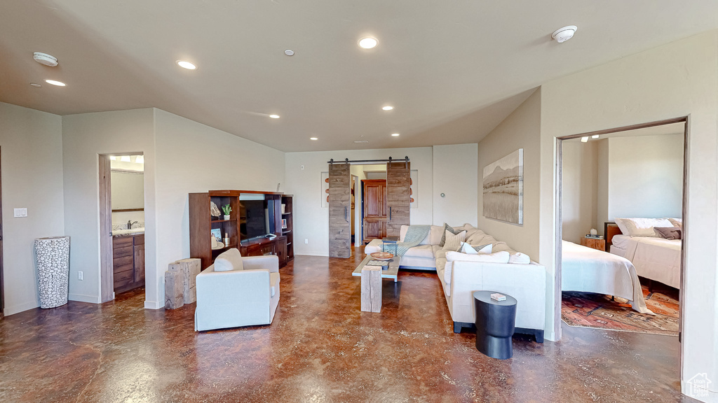 Living room with a barn door, recessed lighting, and concrete flooring