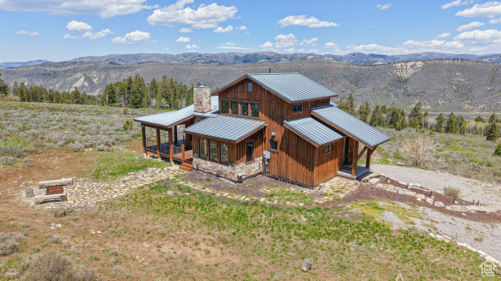 Rear view of property with a standing seam roof, metal roof, a mountain view, a chimney, and board and batten siding