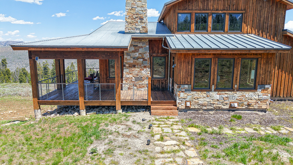View of front of house with stone siding, metal roof, and a chimney
